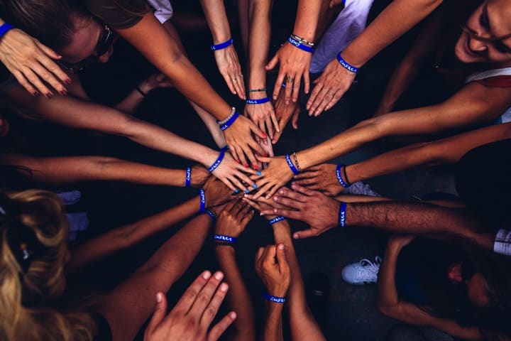 Overview shot of several people putting hands into the center