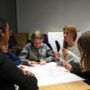 Teenagers sitting around a table talking and brainstorming on a poster sheet