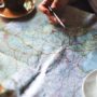 Person looking over a road map at a table with pen in hand