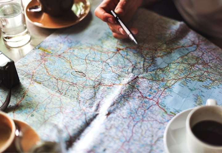 Person looking over a road map at a table with pen in hand