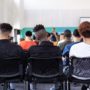 Students sitting and listening to a teacher speak