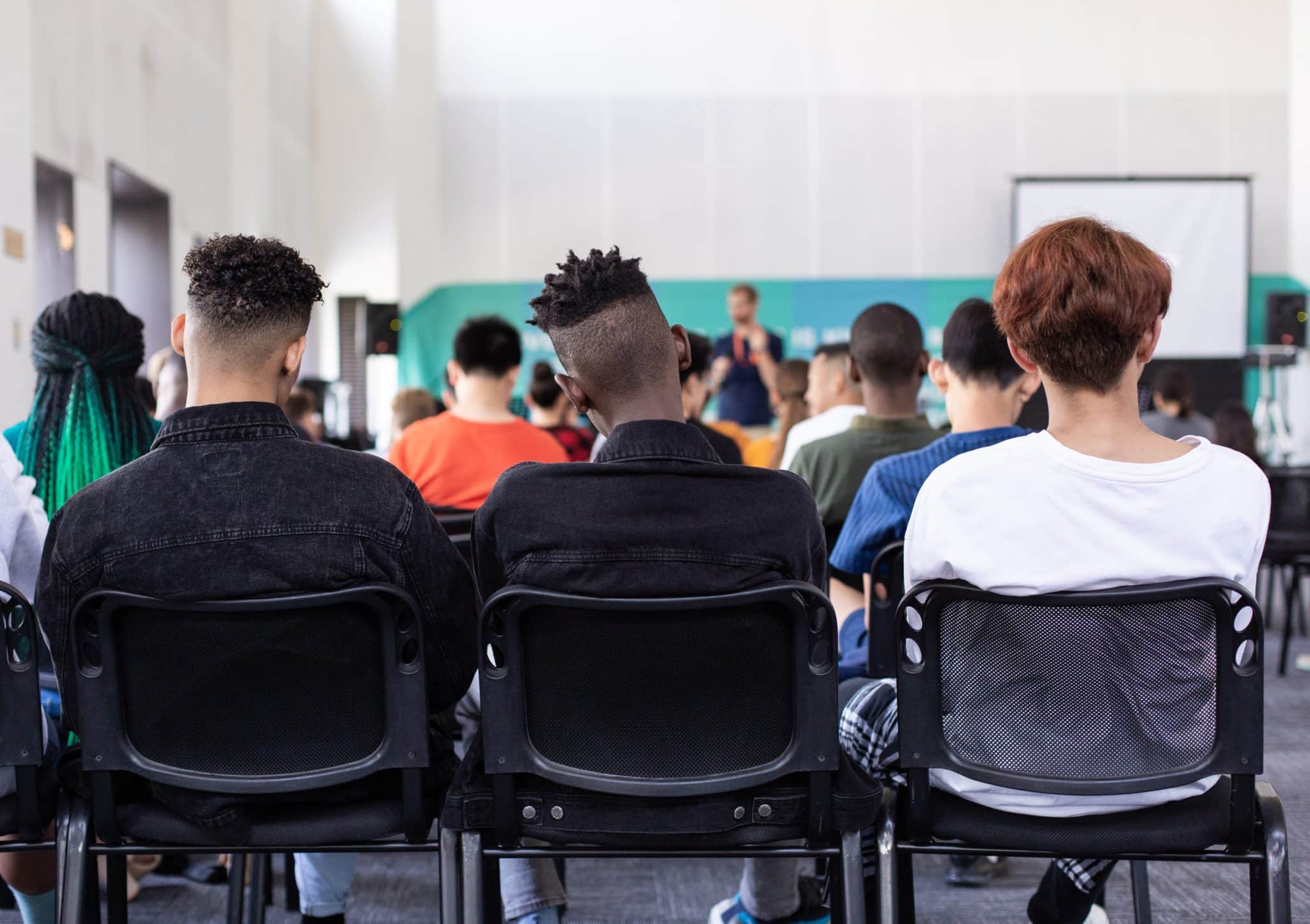 Students sitting and listening to a teacher speak