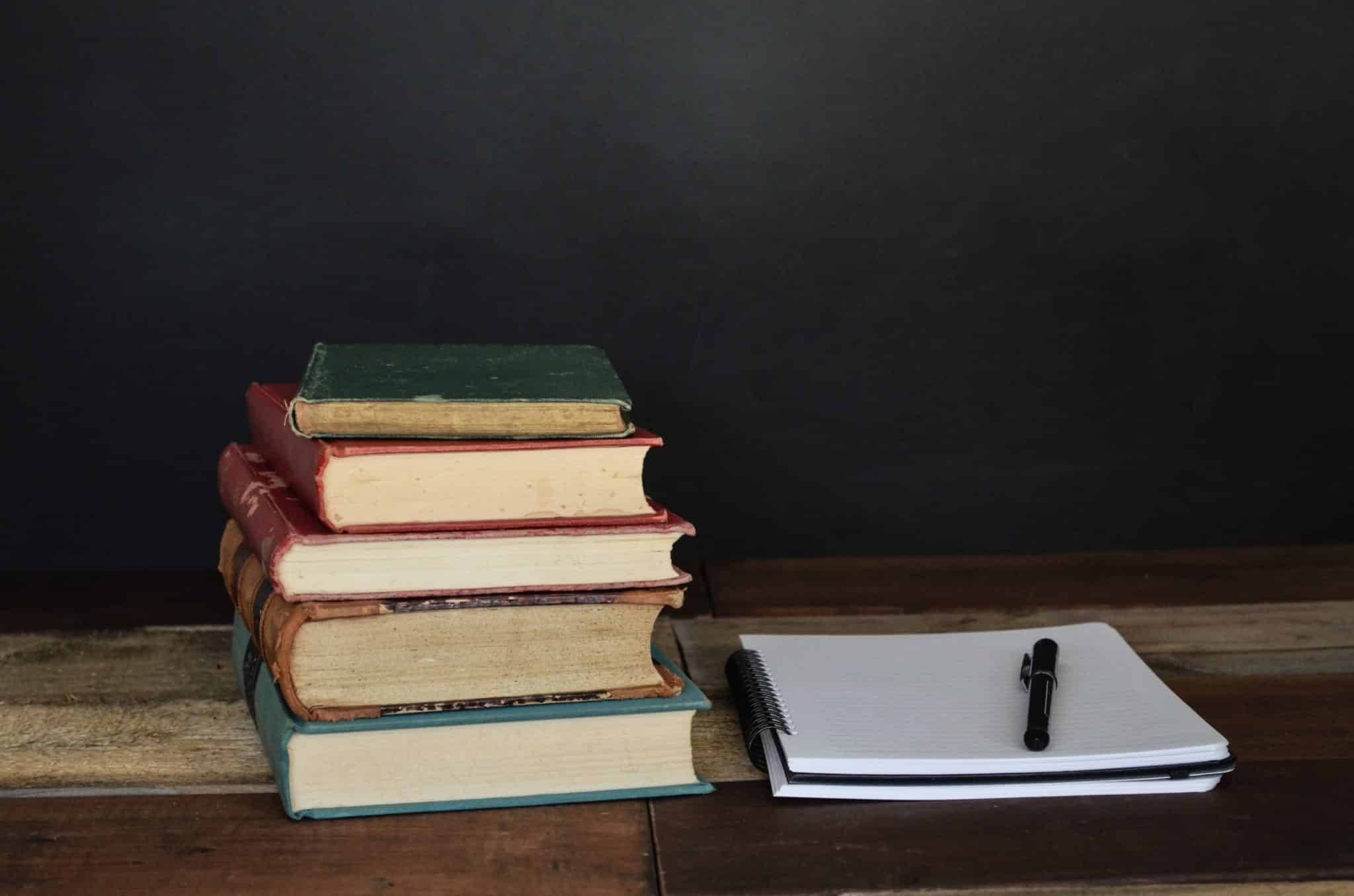 Stack of books and a notebook and pen