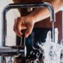 Person filling a water glass from a faucet