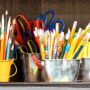 Several containers of pens, pencils, and scissors