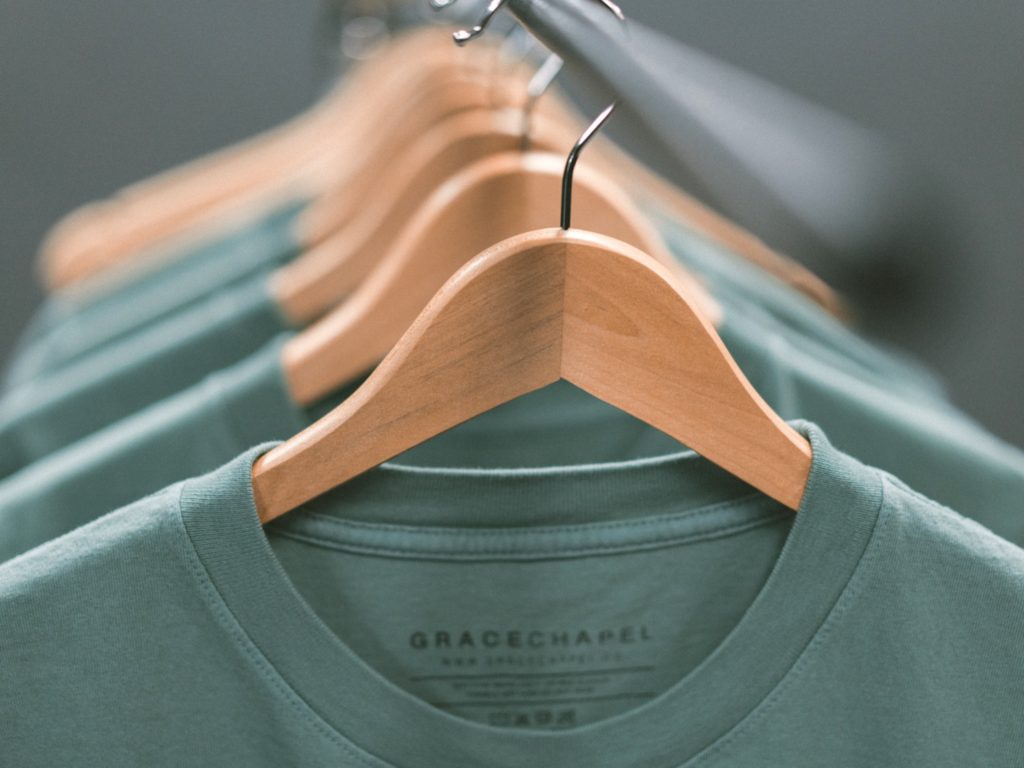 Green t-shirts hanging on a rack 