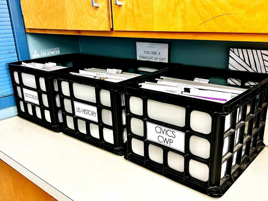 A set of plastic crates containing classroom assignments sitting on a counter 