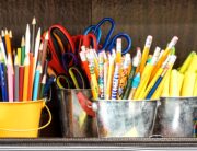 Several containers of pens, pencils, and scissors