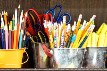 Several containers of pens, pencils, and scissors